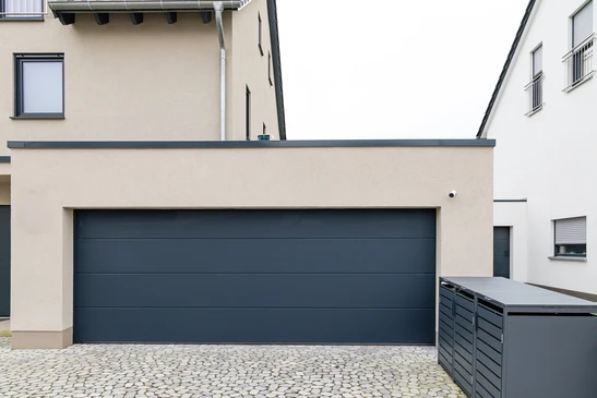 Façade extérieure de garage résidentiel avec deux portes basculantes beiges à lamelles verticales